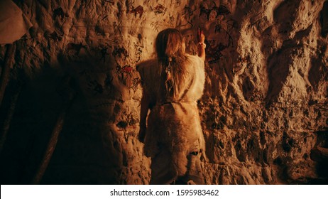 Back View Primitive Prehistoric Neanderthal Child Wearing Animal Skin Draws Animals   Abstracts the Walls at Night  Creating First Cave Art and Petroglyphs  Rock Paintings 