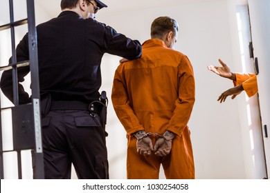 Back View Of Prison Guard Leading Criminal In Handcuffs