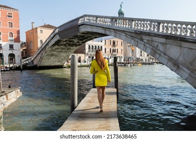 Back View Of Redhead Woman Walking On Pier Near Bridge Over Grand Canal In Venice