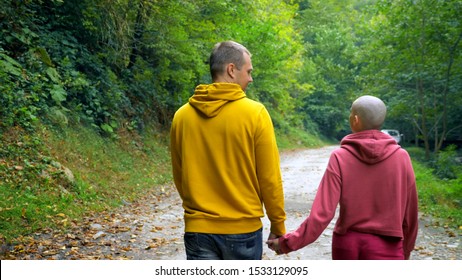 Back View. Romantic Couple Man And Bald Woman Walks In The Autumn Forest