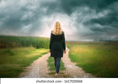 Back View Of A Sad Woman Walks Alone On A Rural Road.