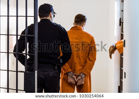 back view of security guard leading criminal in handcuffs