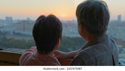 Back View Of Senior Asian Couple Looking Outside From Home