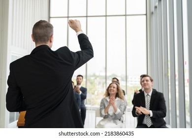 Back View Of Senior Business Man Talking At Podium Speaker. Business People Clapping Hands To Speaker At Business Conference Room