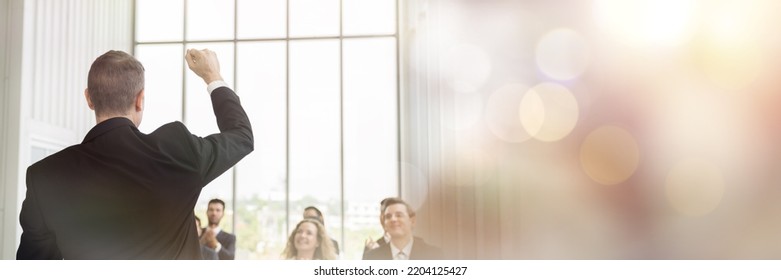 Back View Of Senior Business Man Talking At Podium Speaker. Business People Clapping Hands To Speaker At Business Conference Room. Banner, Bokeh And Light Concept