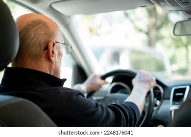 Back view of senior caucasian man with hands over the steering wheel driving his car - Powered by Shutterstock