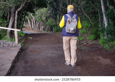 Back view of senior man enjoying nature outdoors in a mountain forest walking in the footpath.  Elderly caucasian man enjoys retirement and healthy lifestyle - Powered by Shutterstock