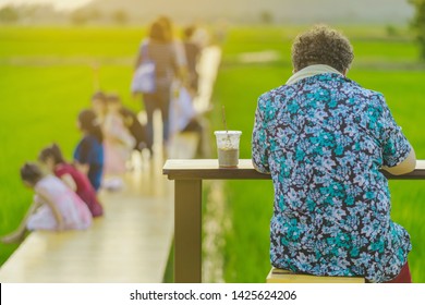 Back view of senior woman sit for resting and waiting for time to take photos of the sunset on the farmer's balcony in the rice fields. - Powered by Shutterstock