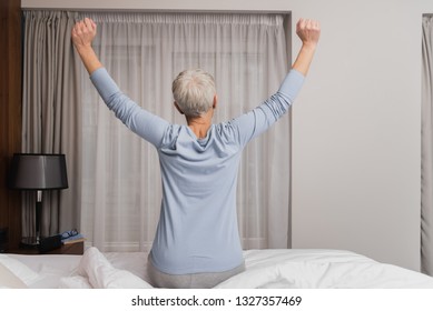 Back View Of Senior Woman Stretching And Getting Ready For Sleep In Her Bedroom, Night Routine Concept