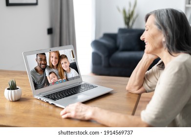 Back View A Senior Woman Using A Laptop For Video Call. An Elderly Mother Is Talking Online With An Adult Daughter And Her Multiracial Family, Video Meeting With A Family On The Distance