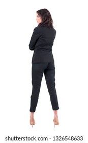 Back View Of Serious Elegant Woman In Black Suit Looking Away With Crossed Arms. Full Body Isolated On White Background. 