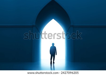 Back view shadow silhouette of young asian muslim man with beard walking alone to mosque entrance door arch at night