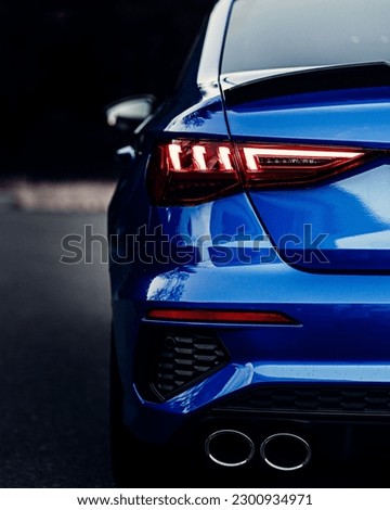 A back view of a shiny blue sport car lights with blur background, vertical shot