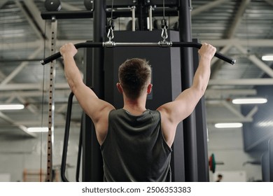 Back view shot of man bulking back muscles via lat pulldown machine - Powered by Shutterstock