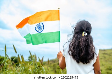 Back View Shot Of Running Girl Kid With Indian Waving Flag In Hand - Concept Of Patriotism, Republic Day Celebration And Freedom