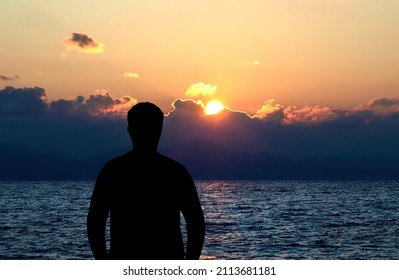 Back view silhouette photo of depressed man watching the sunset. Solitude, abandone, depression, lonliness concept.
