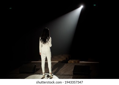 Back View Of A Singer With Microphone Singing A Song On Stage In White Lights.