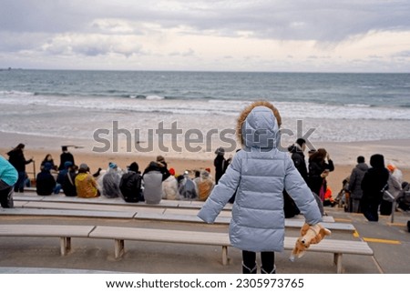 Back view of small child at sea shore waiting to see penguin parade.                             