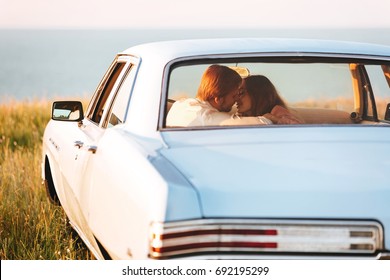 Back view of a smiling attractive couple in love sitting and kissing on a back seat of a car