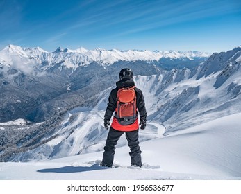 Back view of snowboarder at mountains background in ski resort of Krasnaya Polyana, Russia