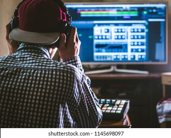 back view of sound engineer in snapback and holding headphones on head monitoring music in studio - Powered by Shutterstock