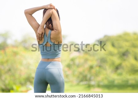 Back view of sport woman warming up outdoors, Fitness woman doing stretch exercise stretching her arms