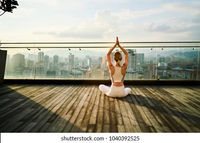 Back view of sports woman feeling inspiration during yoga training on rooftop terrace in metropolis, slim girl in active wear meditating in pose keeping perfect body shape and healthy lifestyle - Powered by Shutterstock