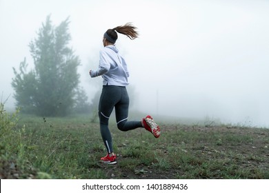 Back view of sportswoman running through misty field in the morning. Copy space. - Powered by Shutterstock