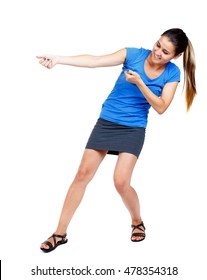 Back View Of Standing Girl Pulling A Rope From The Top Or Cling To Something. Girl Watching. Girl In A Short Skirt And A Blue Shirt Pulling Rope.