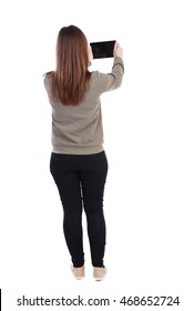 Back View Of Standing Young Beautiful  Woman  Using A Mobile Phone. Girl  Watching. Rear View People Collection.  Backside View Of Person.  Isolated Over White Background. A Girl In A Gray Sweater