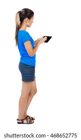 Back View Of Standing Young Beautiful  Woman Using A Mobile Phone Or Tablet Computer. Girl  Watching. Rear View People Collection.  Backside View Of Person.  Isolated Over White Background. Girl In A