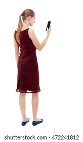 Back View Of Standing Young Beautiful  Woman  Using A Mobile Phone. Girl  Watching. Rear View People Collection.  Backside View Of Person.  Isolated Over White Background. The Girl In The Maroon