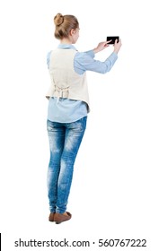 Back View Of Standing Young Beautiful  Woman  In Vest And Using A Mobile Phone. Girl  Watching. Rear View People Collection.  Backside View Of Person.  