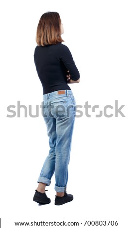 back view of standing young beautiful  woman.  girl  watching. Rear view people collection.  backside view of person. girl in jeans and a black T-shirt is standing sideways with her hands on her chest