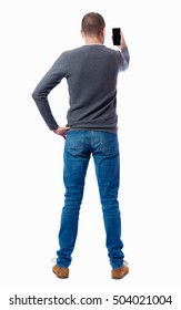 Back View Of Standing Young Man  And Using A Mobile Phone. Girl Watching. Rear View People Collection. Guy In A Gray Sweater Photographed Holding The Phone At Arm's Length.