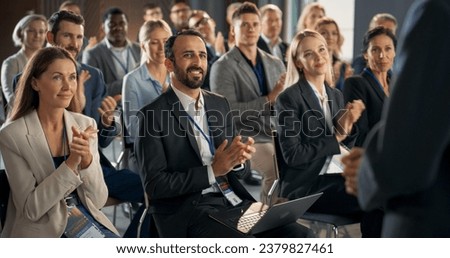 Back View Of Startup CEO Gesturing And Pitching Innovative Product Or Service to Room Full of Diverse Investors. Business People Applauding and Smiling At International Technology Forum.