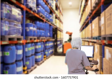 Back View Of A Stock Keeper Working On A Desktop Computer Aseptic Products In The Warehouse.shallow Focus Effect.