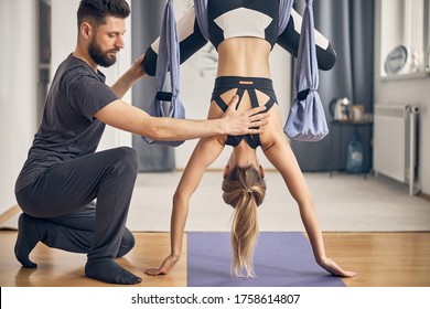 Back view of a strong woman doing an inversion exercise assisted by her personal coach - Powered by Shutterstock