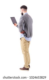 Back View Of Stylish Modern Businessman Holding Tablet With Hand On Hip. Full Body Length Portrait Isolated On White Studio Background.