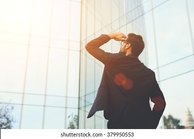 Back View Of Successful Man Entrepreneur Looking Up On Modern Skyscraper While Standing Outdoors, Young Executive Male Director Admires Something On The Distance During Work Break Outside Of Company