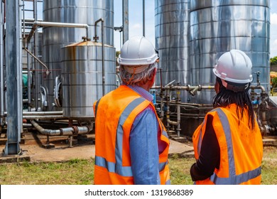 Back view of successful older business manager in discussion with employee on site at chemical plant. Diversity of ethnic background, Caucasian and African American, age and gender.Non urban. Outdoors - Powered by Shutterstock