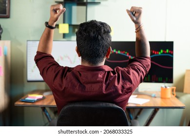 Back view of successful Trader celebrating for profit on shares by looking charts or graphs on computer at office - concept of exited crypto investor , bullish or bearish stock market.
