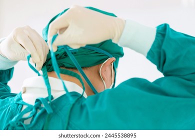 Back view of surgeon tying surgical cap in preparation, Medical team performing surgical operation in operating room, Team surgeon at work in operating room
 - Powered by Shutterstock