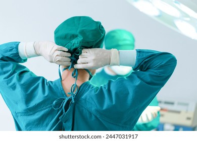 Back view of surgeon tying surgical cap in preparation, Medical team performing surgical operation in operating room, Team surgeon at work in operating room
 - Powered by Shutterstock