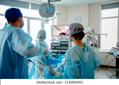 Back view of surgeons team looks at monitors while preforming operation in hospital operating theater, male surgeon operating patient working with surgical laparoscopy instruments. Gynecology. - Powered by Shutterstock