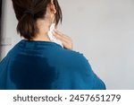 back view of sweating woman with wet cloth because of hot weather in summer time, menopause symptom concept 