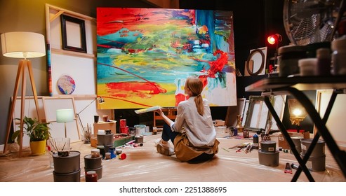 Back view of talented concentrated Caucasian woman professional artist sitting on floor in studio in evening painting drawing on big canvas, creativity work, contemporary creative painter - Shutterstock ID 2251388695