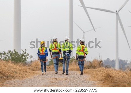 Back view, Teamwork engineer worker wearing safety uniform discuss operational planning at wind turbine field renewable energy. technology protect environment reduce global warming problems.