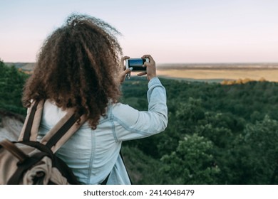 Back view of teenage taking picture of landscape