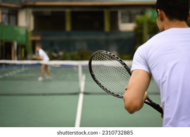 Back view of tennis player standing in ready position to receive a serve, practicing for competition on a court - Powered by Shutterstock